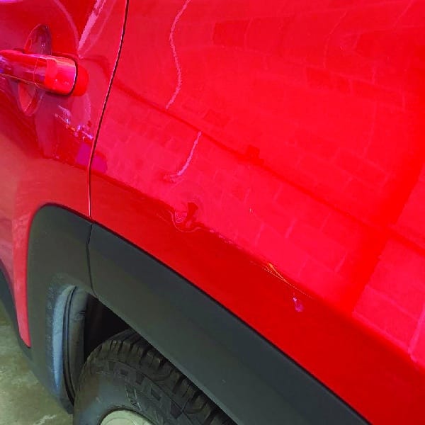 1/2 of part of a sliding image with a car dent on a red car. It is demonstrating a dent removed that can performed by TintBusiness for your USA car